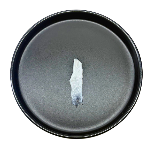Dark gray ceramic plate with a small piece of white ceramic on a white background