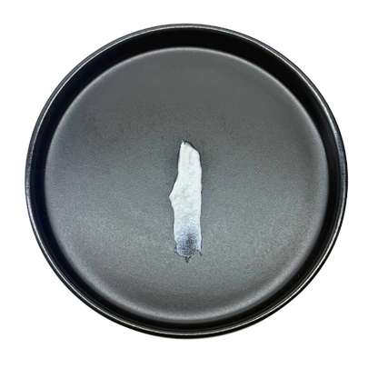 Dark gray ceramic plate with a small piece of white ceramic on a white background