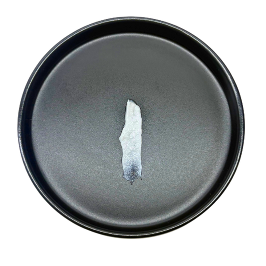 Dark gray ceramic plate with a small piece of white ceramic on a white background