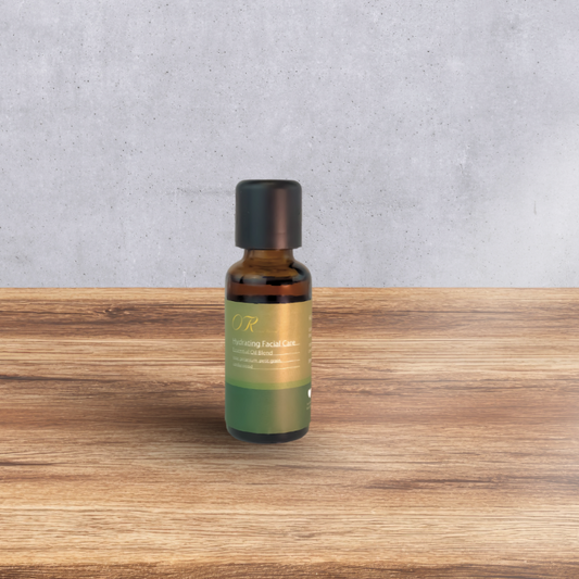 A small amber glass bottle with a black cap and a green-to-gold label reading 'OR Nourishing Facial Care,' standing on a wooden surface against a light gray wall.