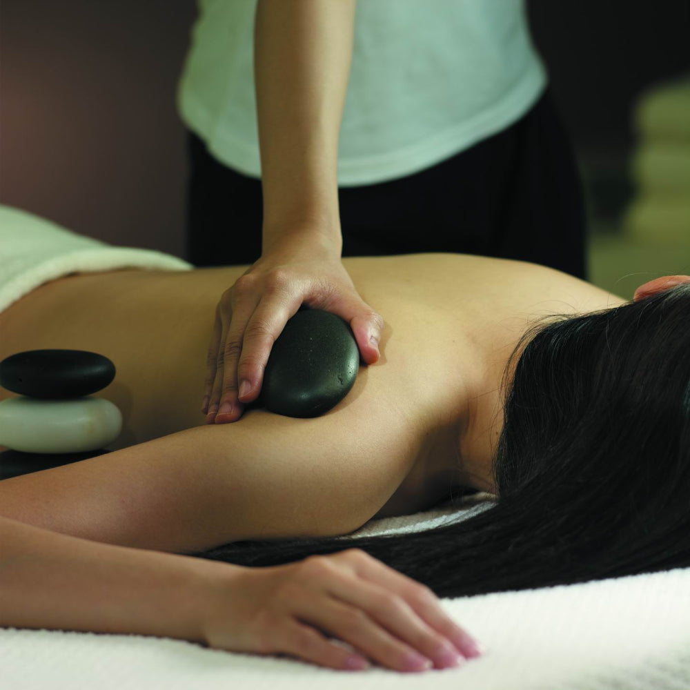 Person receiving a hot stone massage with a blurred background