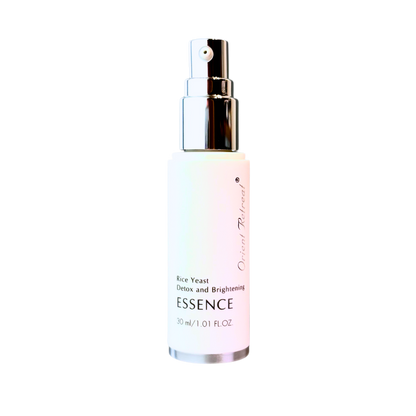 A 30 ml spray bottle of Essence Detox and Brightening Rice Yeast Essence by Origin Refined, featuring a white bottle with a soft pink tint near the bottom, a silver pump, and black text, set against a plain white background.