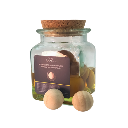 Glass jar with cork lid containing wooden Orr Arima diffuser and bath bombs on a white background