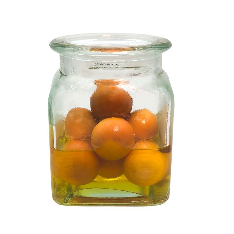 Clear glass jar filled with oranges on a white background